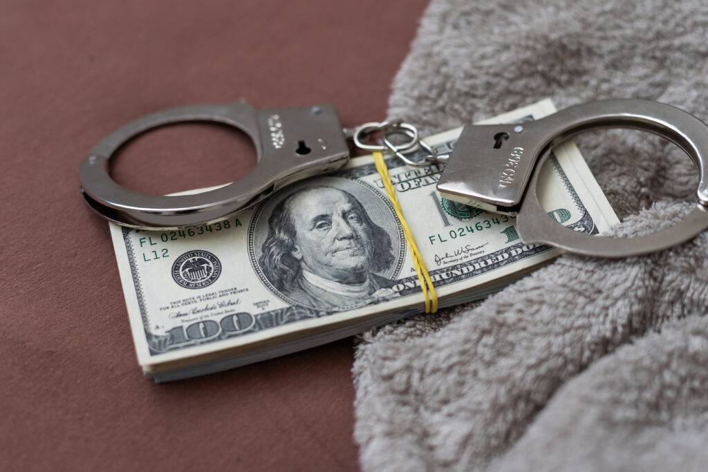 Handcuffs and money representing the bail bonds process with Allstate Bail Bonds, available 24/7 in Ohio.